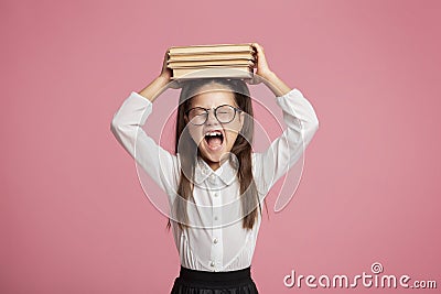 Little girl with glasses holds stack of books on her head and shouts Stock Photo