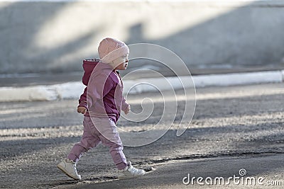 Little girl goes on the empty street. Child abandoned on street. Toddler walks alone Stock Photo