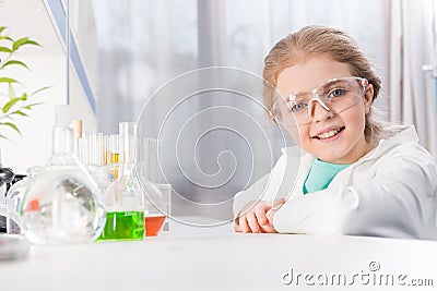 Little girl in goggles with flasks in laboratory looking at camera Stock Photo