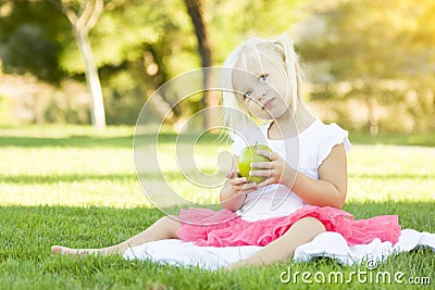 Little Girl In Grass Eating Healthy Apple Stock Photo