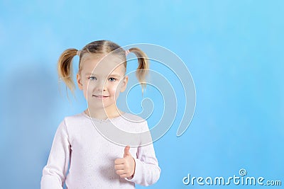 A little girl with a hair two tails. Cute baby with blond hair showing sign super. Stock Photo