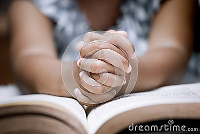 Little girl hands folded in prayer on a Holy Bible Stock Photo