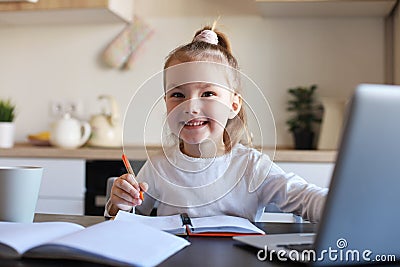 Little girl handwrite study online using laptop at home, cute happy small child take Internet web lesson or class on PC Stock Photo