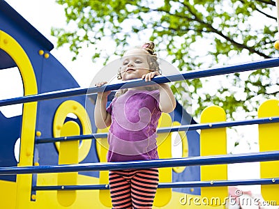 Little girl hanging on the crossbar on the playground Stock Photo