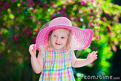 Little girl in a hat in blooming summer garden Stock Photo