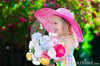 Little girl in a hat in blooming summer garden Stock Photo
