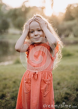 The little girl with her hands on her head and smiles Stock Photo