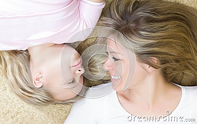 Little girl and her mother lying together indoor. Stock Photo