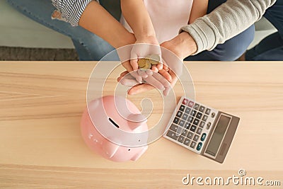 Little girl and her parents with coins and piggy bank at home. Money savings concept Stock Photo