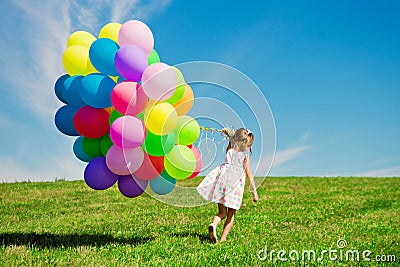 Little girl holding colorful balloons. Child playing on a green Stock Photo