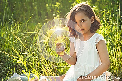 Little Girl holding a the cross in hand during beautiful sunset. Hands folded in prayer concept for faith Stock Photo