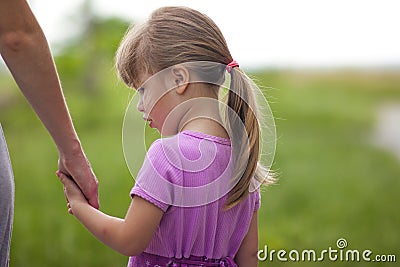 Little girl holding a hand of her mother. Family relations concept. Stock Photo