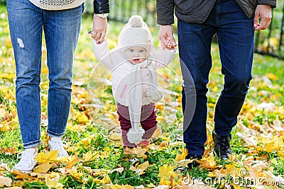 Little girl holding hands of parents, going on autumn park Stock Photo