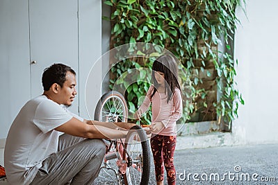 little girl holding a wrench while pedaling with her father Stock Photo