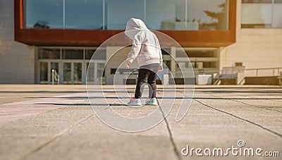 Little girl with hoodie looking her sneakers outdoors Stock Photo