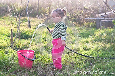 Little girl with hose in the garden Stock Photo