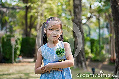 Little girl hugging small artificial plant Stock Photo