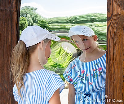 Little girl imakes a face n front of distorting mirror Stock Photo