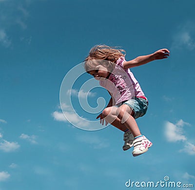 A little girl jumping against the blue sky background Stock Photo