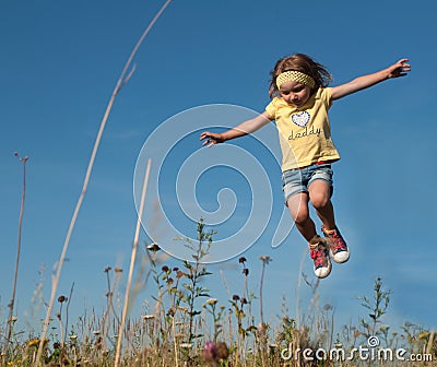 A little girl jumping against the blue sky background Stock Photo