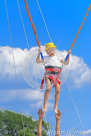 A little girl jumps high on a trampoline with rubber ropes again Stock Photo