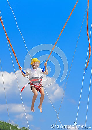 A little girl jumps high on a trampoline with rubber ropes again Stock Photo