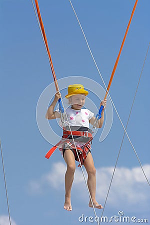 A little girl jumps high on a trampoline with rubber ropes again Stock Photo