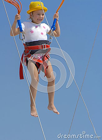 A little girl jumps high on a trampoline with rubber ropes again Stock Photo