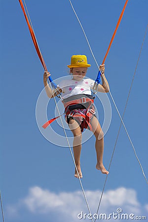 A little girl jumps high on a trampoline with rubber ropes again Stock Photo