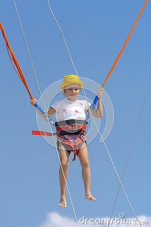 A little girl jumps high on a trampoline with rubber ropes again Stock Photo