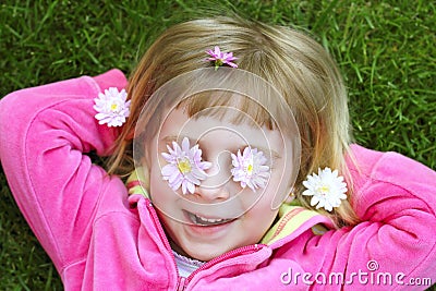 Little girl laying grass daisiy flowers in eyes Stock Photo