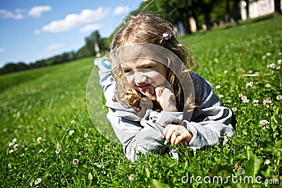 Little girl lies on a green field Stock Photo