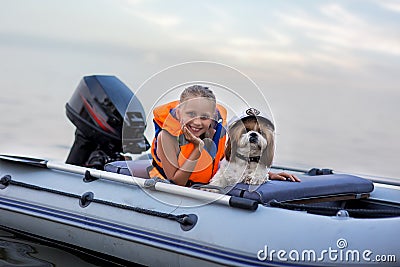 Little girl in a life jacket with her dog in a boat on the lake. Safety. summer rest Stock Photo