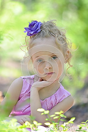 Little girl in a lilac dress with a flower in her hair Stock Photo