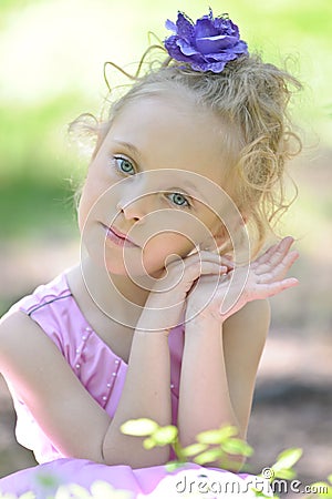 Little girl in a lilac dress with a flower in her hair Stock Photo