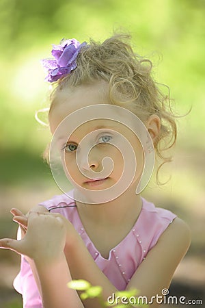 Little girl in a lilac dress with a flower in her hair Stock Photo