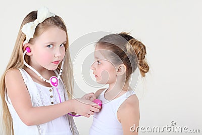 Little girl listens heartbeat of another girl by toy phonendoscope Stock Photo