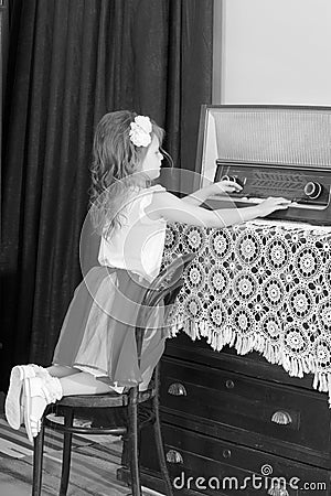 Little girl listens to old radio. Stock Photo