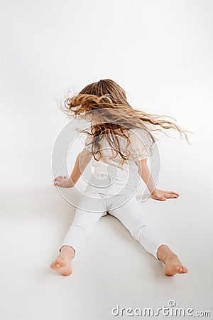 little girl with long hair sits on floor, and waving his head, hair is flying Stock Photo