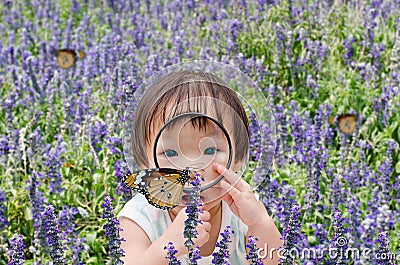 Little girl looking at butterfly with magnifying glass Stock Photo