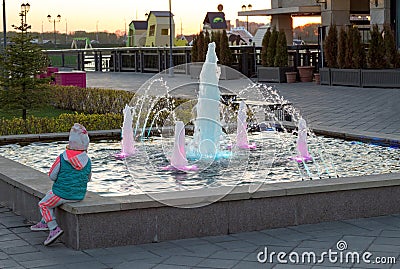 Little girl looks at the fountain at sunset on the Embankment of the city Editorial Stock Photo