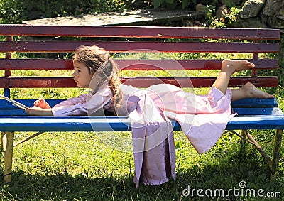 Little girl lying on bench Stock Photo