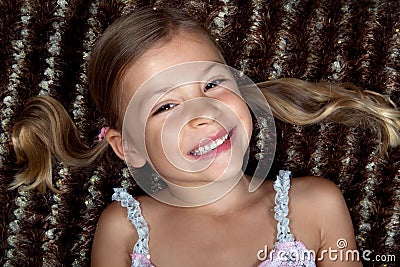 Little girl lying down on a rug and smiling Stock Photo