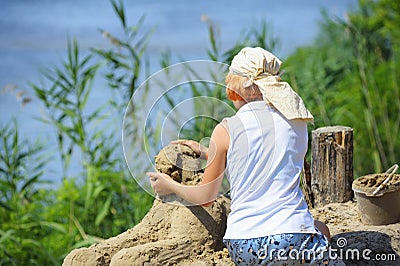 Little girl making a sand sculpture on a beach of a river Editorial Stock Photo