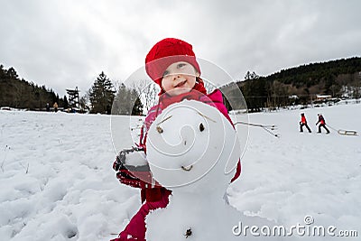 Little girl making snowman winter day Stock Photo