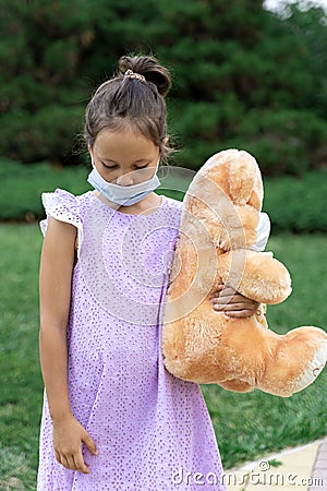 A little girl in a medical mask is waiting for the end of the quarantine and misses a normal life Stock Photo