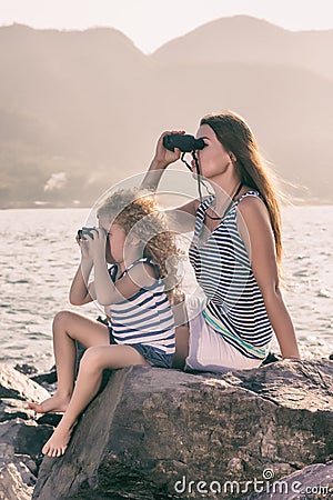 Little girl and mother looking far away with binoculars Stock Photo