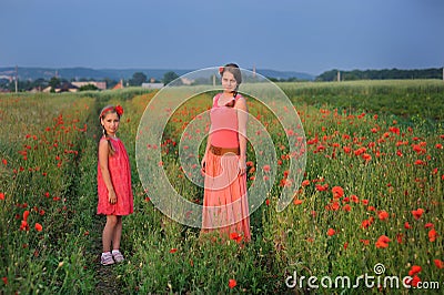 Little girl with mother walking on the poppy field Stock Photo