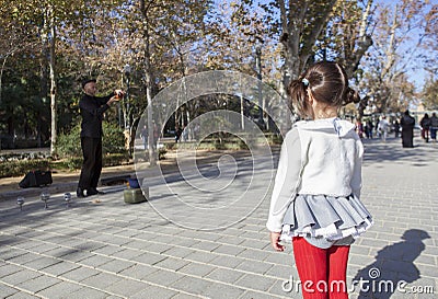 Little girl observes a juggler with crystal balls shows Editorial Stock Photo