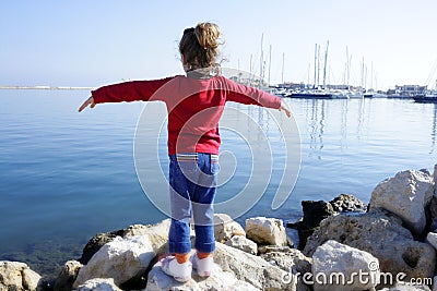 Little girl open arms looking marina blue sea Stock Photo